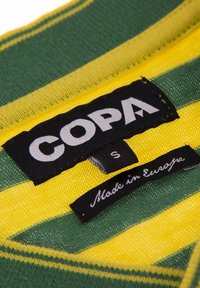 Grön och gulrandig tyg med en svart etikett som säger "COPA" och storlek "S"; en mindre etikett uppger "Tillverkad i Europa."