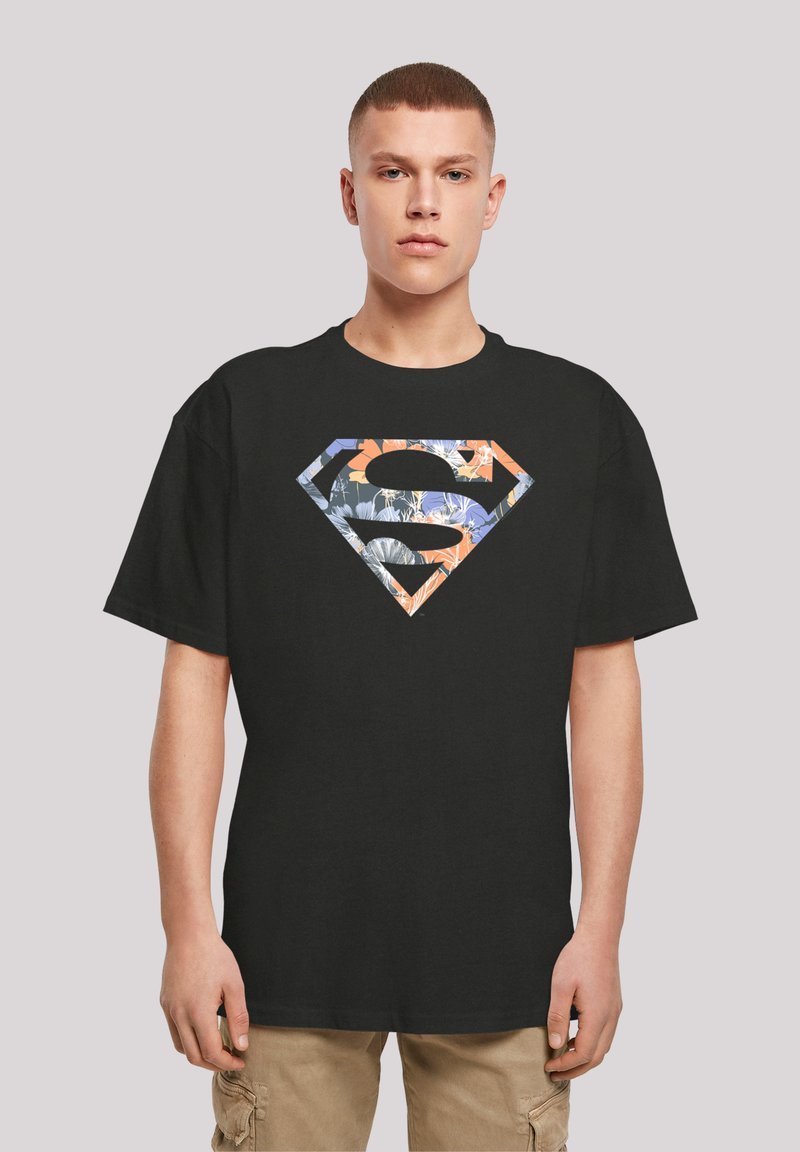 Black cotton t-shirt featuring a large, multi-patterned Superman logo in orange, blue, and white, with a loose fit and short sleeves.