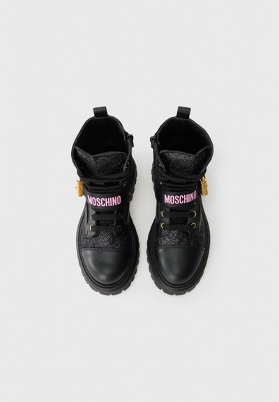 Sorte ankelstøvler laget av lær og glitrende materiale, med rosa "MOSCHINO" merke, gull detaljer og teksturerte såler.