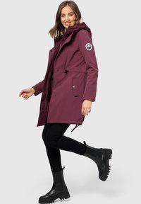 Maroon parka jacket with a hood, front zip closure, side pockets, and adjustable waist; features logo patch on sleeve and black accents.