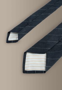 Cravată albastru închis din țesătură texturată cu dungi diagonale, având o captuseală interioară cu dungi de culoare deschisă și vârfuri ascuțite.