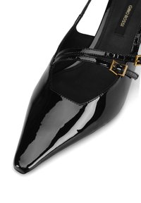 Juodų patentuotos odos aukštakulniai bateliai su smailia nosimi, kryžminėmis dirželiais su auksinės spalvos sagtimis, lygiu paviršiumi ir išpjautomis šoninėmis detalėmis.