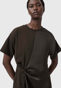 Tmavohnedé tričko s okrúhlym výstrihom, krátkymi rukávmi a skrúteným uzlom v oblasti pásu, z hladkej látky a vo voľnom strihu.