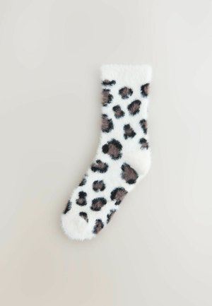 Fuzzy hvid sok med leopardmønster med brune og sorte pletter. Blød tekstur, ankellang design.