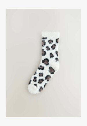 Calcetín blanco difuso con un patrón de leopardo que presenta manchas marrones y negras. Textura suave, diseño hasta el tobillo.