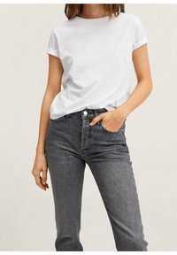 T-shirt bianco in cotone con maniche arrotolate abbinato a jeans grigio scuro a vita alta. L'outfit presenta un design aderente e una texture morbida.