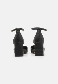 Black heeled sandals with a textured faux leather upper, block heel, and ankle strap. Features smooth inner lining and open heel design.