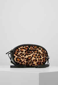 Leopardmönstrad axelväska med svart läderdetalj, oval form, justerbar rem och dragkedjestängning. Mjuk textur och djurmönster.