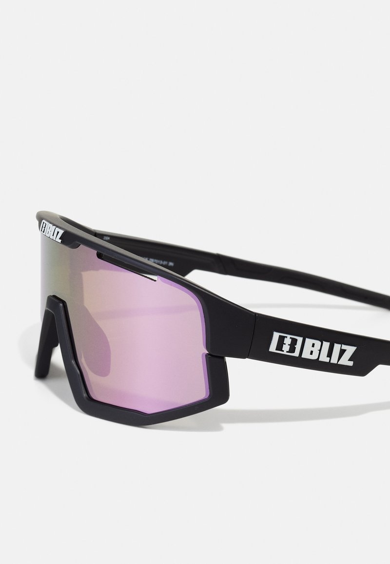 Czarne sportowe okulary przeciwsłoneczne o geometrycznym wzorze, z różowymi soczewkami lustrzanymi i białymi akcentami logo na zausznikach. Lekka plastikowa oprawa.