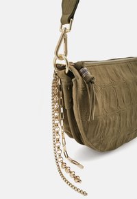 Borsa in camoscio verde oliva con motivo testurizzato, chiusura con zip e accessori in metallo color oro. Include una tracolla a catena rimovibile.