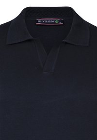 Schwarzes Poloshirt mit einem strukturierten Kragen, weichem Körper und einem Etikett mit der Aufschrift "FELIX HARDY" am Hals.
