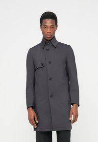 Ciemnoszary płaszcz trencz z wysokim kołnierzem, pięcioma guzikami i bocznymi kieszeniami; gładka faktura i dopasowany krój sięgający do bioder.