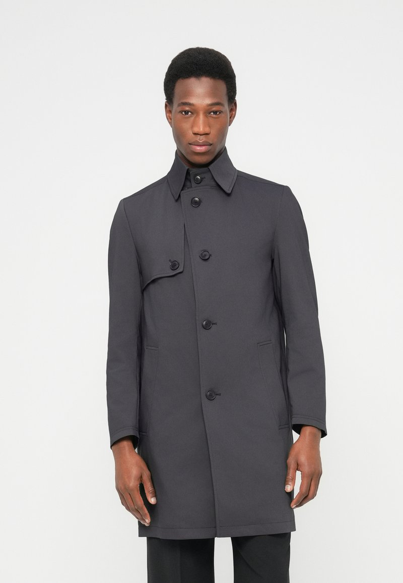Ciemnoszary płaszcz trencz z wysokim kołnierzem, pięcioma guzikami i bocznymi kieszeniami; gładka faktura i dopasowany krój sięgający do bioder.