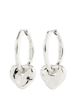 Strieborné kruhové náušnice s hladkým, zaobleným príveskom v tvare srdca visiaci z každého kruhu na bielom pozadí.