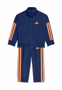 Tmavomodrá tepláková súprava z ľahkej látky, s oranžovými pruhmi na rukávoch a nohaviciach, so zapínaním na zips a vyšitým logom.