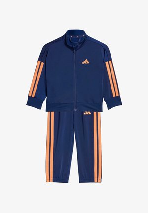 Marinblå träningsdress i lätt tyg, med orange ränder på ärmar och byxor, en jacka med dragkedja och ett broderat märke.