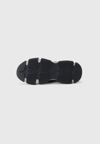 Black athletic shoe sole with rubber traction patterns, rounded toe, and a smooth, textured midsole featuring grey accents.