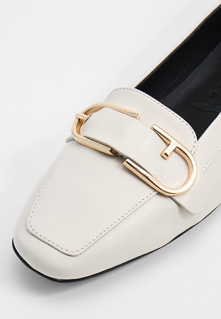 Weiße Lederloafer mit quadrater Spitze und einem auffälligen goldfarbenen Schnallen-Detail auf der Vorderseite, in glatter Textur und minimalistischer Gestaltung.