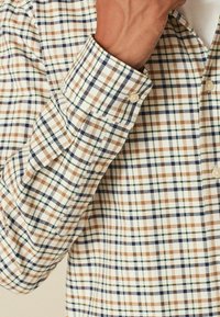 Geblokt overhemd in beige, bruin, groen en marineblauw. Katoenen stof met een knoopmanchet en een klassieke kraag. Bevat kleine, gelijkmatig verspreide vierkanten.