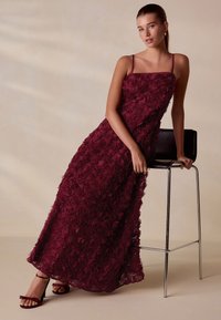 Bordeauxrode bloemen maxi-jurk met 3D rozenapplicaties, spaghettibandjes en een vloeiende silhouet, gecombineerd met bijpassende sandalen met bandjes.