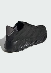 Black athletic shoe with a textured knit upper, three striped accents, and a cushioned, molded black sole. Features a heel pull tab.
