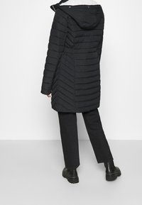 Svart vadderad jacka med huva, med quiltad design, sidofickor och midjelång modell. Slät textur och slitstarkt tyg.