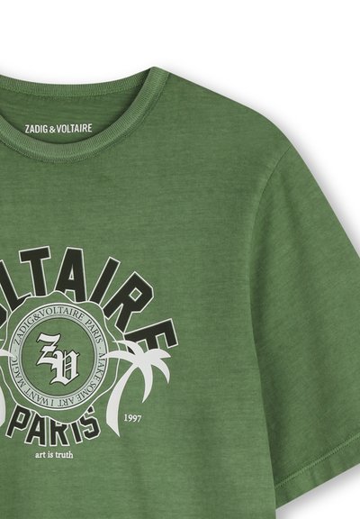T-shirt en coton vert olive avec un col rond, arborant une impression graphique "Zadig & Voltaire" et des palmiers en blanc et noir.