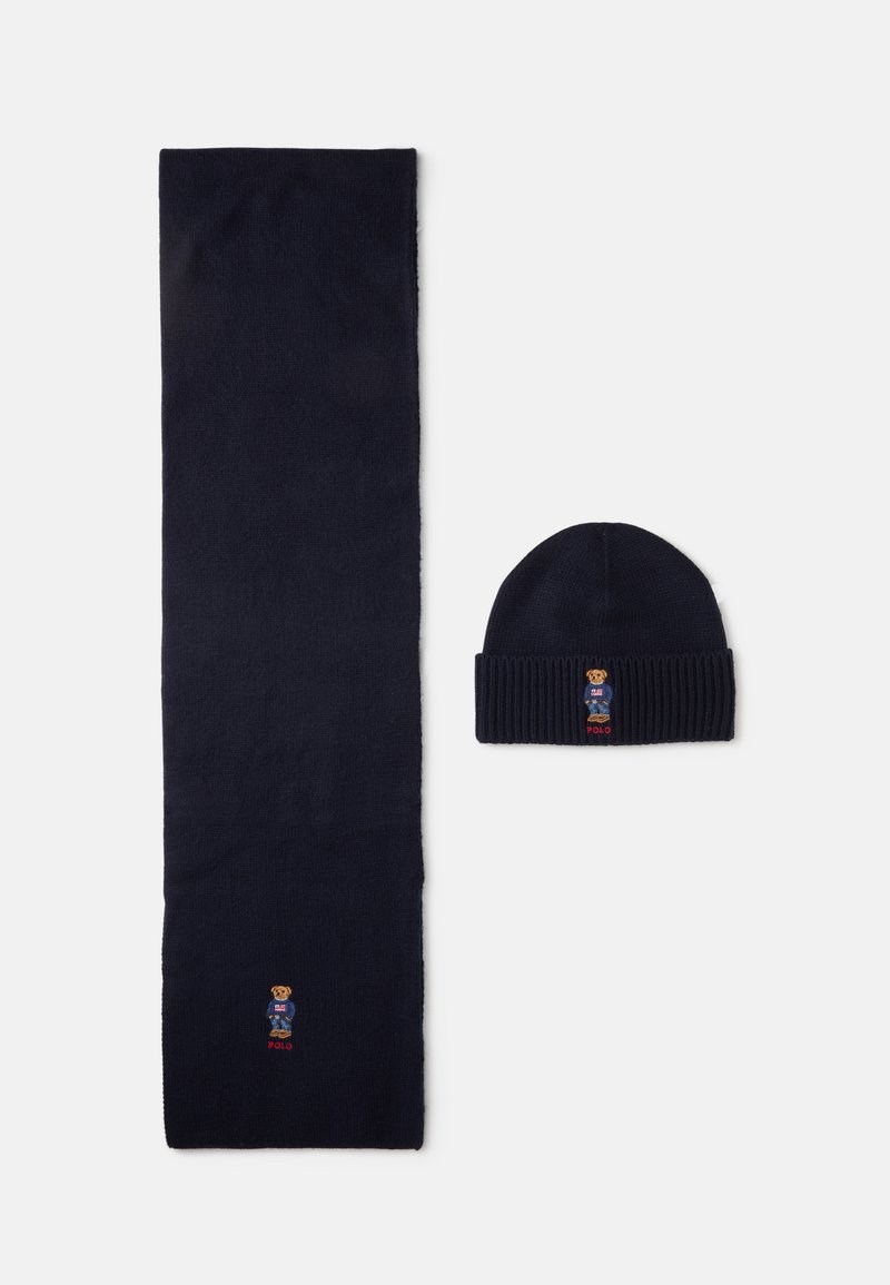 Ναυτικό πλεκτό σκουφί με ριγωτό μανίκι και ταιριαστό κασκόλ που διαθέτει κεντημένο λογότυπο αρκούδας και κείμενο, κατασκευασμένο από μαλακό ύφασμα.