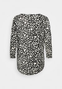 Haut à manches longues noir et blanc avec un col rond, présentant un motif à pois et un ourlet arrondi. Fabriqué en tissu léger.