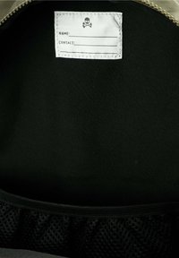 Interior negro de una bolsa con una etiqueta blanca que presenta un gráfico de calavera. La etiqueta tiene espacios en blanco para un nombre y la información de contacto.
