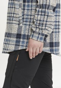 Geruite overhemd in lichtgrijs, blauw en marineblauw met lange mouwen en knoopmanchetten, gecombineerd met zwarte textuur broek met accentzakken.