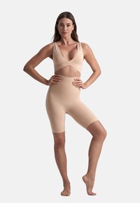Set di abbigliamento attivo nudo con scollatura a V profonda e design incrociato, con pantaloni elasticizzati che arrivano a metà coscia, realizzati in un materiale morbido e stretchy.