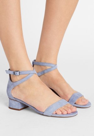 Jasnoniebieskie sandały zamszowe na niskim obcasie typu blok, z paskiem wokół kostki i odkrytymi palcami. Gładka faktura i minimalistyczny styl.
