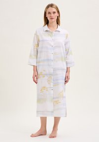 Abito camicia in tessuto leggero, caratterizzato da un motivo floreale ad acquerello in morbidi pastelli di verde, giallo e blu. Maniche lunghe, lunghezza fino al ginocchio.