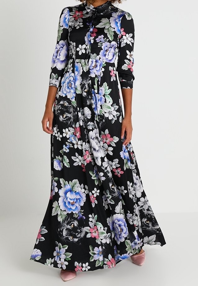 Robe maxi fleurie avec un fond noir, des manches longues et un col boutonné. Décorée de fleurs colorées et d'une silhouette fluide.