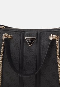 Sac à main Guess noir avec bretelles en chaîne dorée, motif texturé et logo triangulaire Guess USA à l'avant.