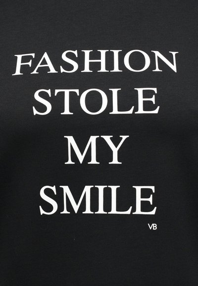 Μαύρο ύφασμα με λευκό κείμενο που γράφει "FASHION STOLE MY SMILE" με κεφαλαία γράμματα.