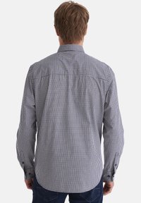 Ein Hemd mit Knöpfen, das ein schwarz-weißes Karomuster, lange Ärmel, geknöpfte Manschetten und ein klassisches Kragen Design aufweist.