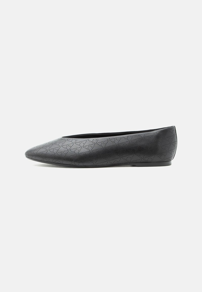Chaussure plate noire à bout pointu avec un motif perforé subtil en forme de losange et un petit talon, vue de côté sur un fond blanc uni.