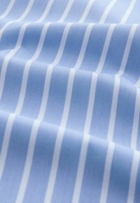 Tissu bleu clair avec des rayures verticales blanches, texture lisse, finition légèrement scintillante, plis créant profondeur et mouvement.