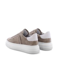 Beige Wildledersneaker mit dicker weißer Gummisohle, gewellten Akzenten an der Ferse und den Seiten sowie strukturiertem Schnürdetail.