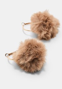 Orecchini in pelliccia sintetica con una forma arrotondata e fluffy di colore marrone chiaro, attaccati a un anello in metallo dorato. Texture morbida con un aspetto voluminoso.