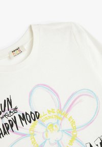 Biała bawełniana koszulka z krótkim rękawem, z kolorową grafiką kwiatu oraz napisem w czerni i żółci. Miękka tekstura, casualowy design.