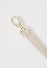 Beige leather strap with stitching detail, featuring a gold-tone metal snap hook clasp. Smooth texture and sleek design.