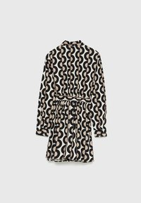 Robe noire et crème présentant un motif géométrique de cercles superposés, avec des manches longues, un col et une taille cintrée se terminant par une jupe évasée.