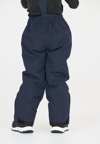 Pantalons de neige imperméables bleu marine avec taille élastique et bretelles ajustables. Bas renforcés et zips sur les côtés pour plus de praticité.