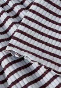 Bawełniana tkanina z naprzemiennymi wąskimi bordowymi i jasnoniebieskimi paskami. Tekstura jest żebrowana, o miękkim wykończeniu i surowych krawędziach.