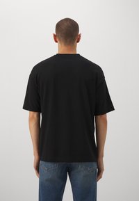 Sort bomulds T-shirt med rund hals, afslappet pasform og korte ærmer, parret med lyseblå denim jeans. Minimalistisk design uden grafik.