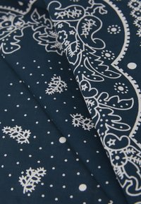 Cotton fabric featuring a dark blue background with white floral and dot patterns, showcasing intricate detailing and smooth texture.