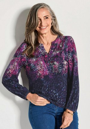 Langarm blouse in donkerpaars met een bloemenpatroon in roze en wit. Heeft een V-hals en elastische manchetten, gemaakt van zachte stof.